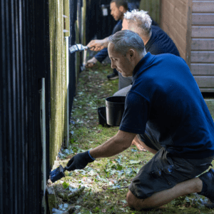 Several men painting a garden fence